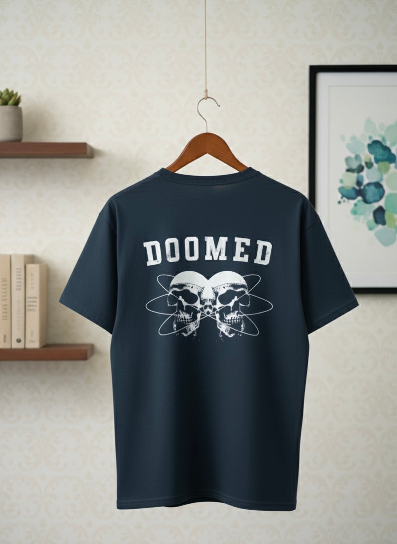 Navy Blue t-shirt with 'DOOMED' text and skull design on a hanger against a neutral wall.